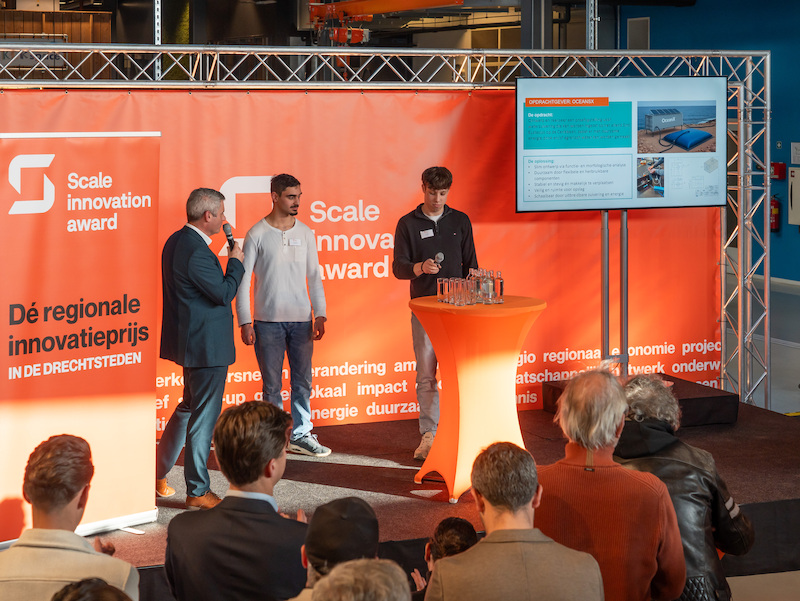 Directeur Duurzaamheidsfabriek en twee studenten ROC Da Vinci College staan op het podium tijdens de Scale Innovation Award