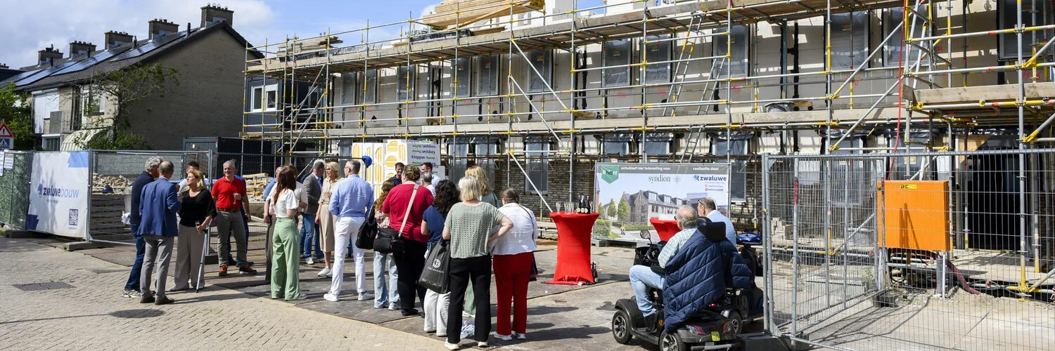 Groep mensen bestaande uit toekomstige bewoners, woningcorporaties en de gemeente vieren feestelijk moment voor de bouw van 33 zorgwoningen