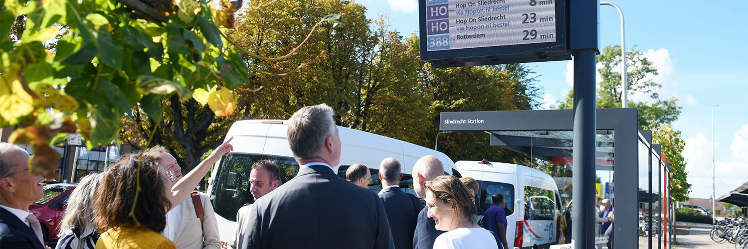 Groep personen wacht bij bushalte station Sliedrecht op Hop On bus