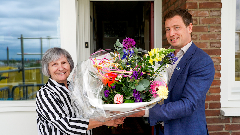mevrouw Tripe ontvangt bloemen als 13.000ste klant, uit handen van Joey Reedijk, programmamanager energietransitie Drechtsteden.