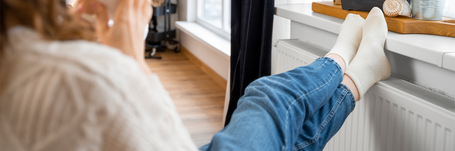 Vrouw met voeten op de verwarming in huis
