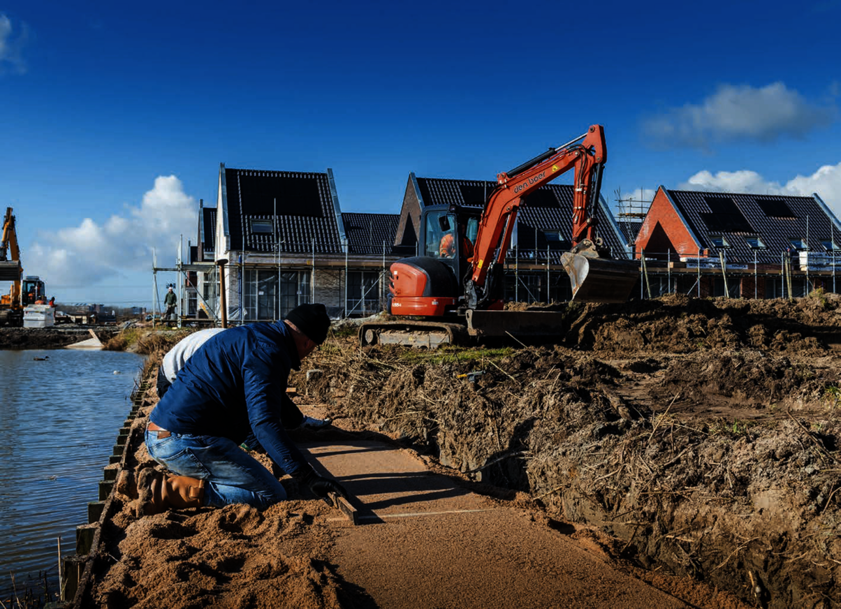 Een man voor een huis die in aanbouw is